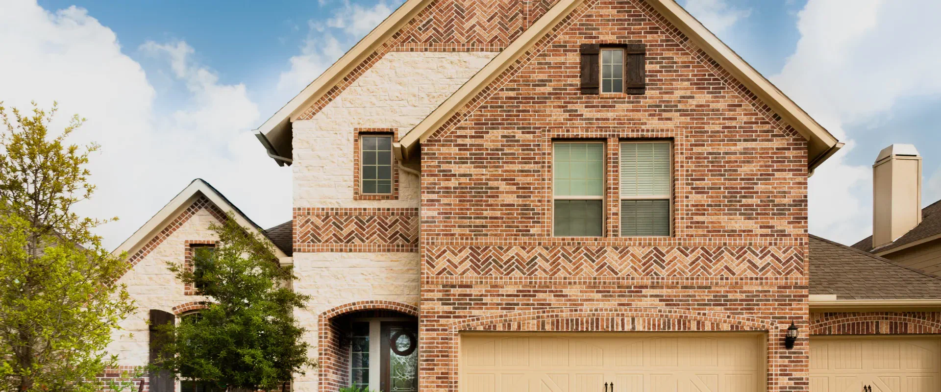 beige bricked wall house with some trees outside and beige garage doors alvin tx